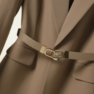 Close-up of a beige trench coat with a belt and gold buckle on a beige background