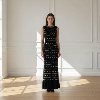 Woman wearing a black dress with white patterns in a bright room with wooden floor and white walls.