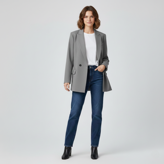 Woman wearing a gray blazer, white shirt, blue jeans, and black shoes on a light gray background