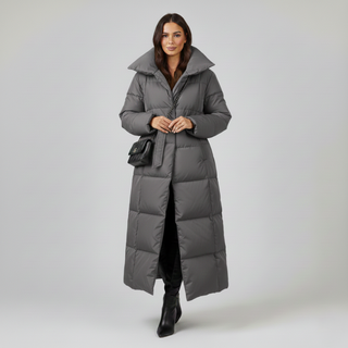 Woman wearing a long gray puffer coat on a white background