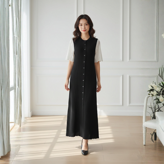 Woman wearing a black and white dress in a bright room with white walls and a vase of flowers.
