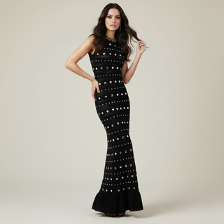 Woman wearing a black dress with white embellishments on a plain background