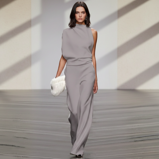 Model wearing a gray dress on a runway with a minimalistic background