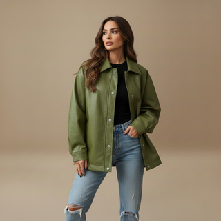 Woman wearing a green jacket and blue jeans against a beige background