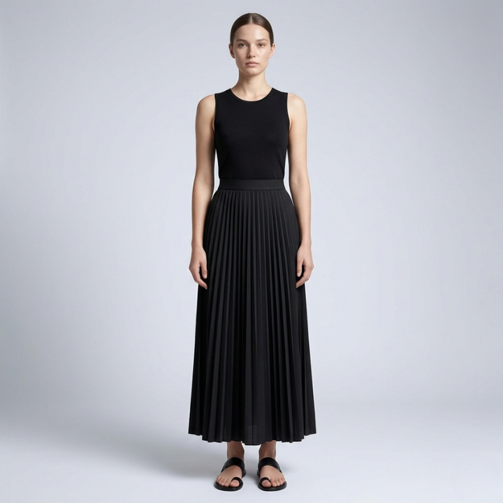 Woman wearing a black sleeveless top and pleated skirt on a light gray background