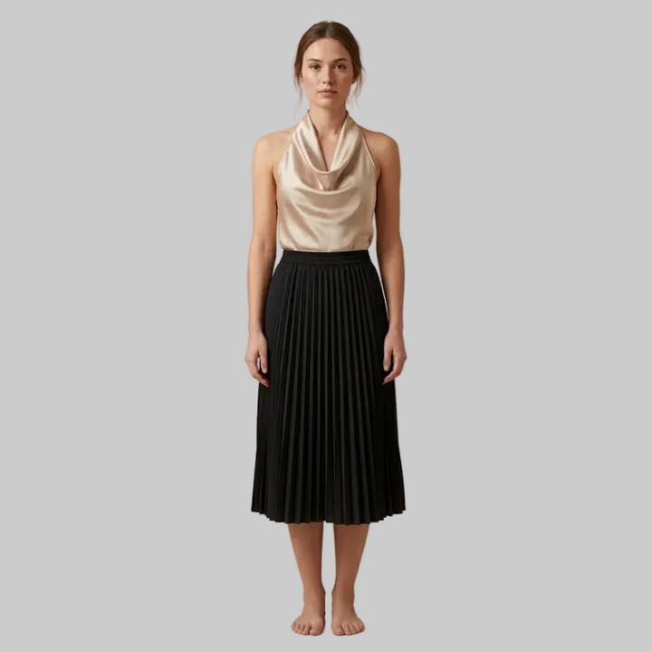 Woman wearing a beige sleeveless top and black pleated skirt on a beige background