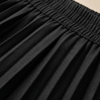 Close-up of black pleated fabric with a beige background