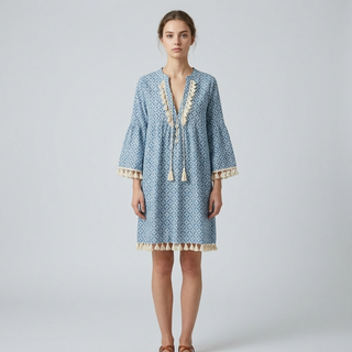 Woman wearing a blue patterned dress with lace details on a light gray background