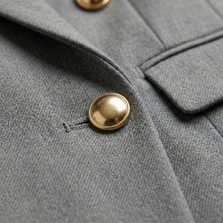 A macro close-up of the premium charcoal grey suit fabric and a detailed metallic gold button fastening.
