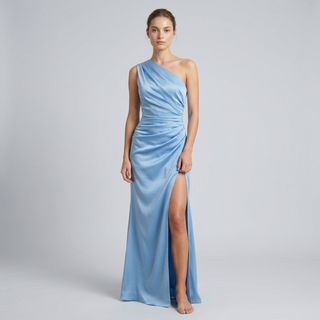 Woman wearing a light blue one-shoulder gown with a slit on a gray background