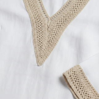 Close-up of a white shirt with beige crochet trim on a white background