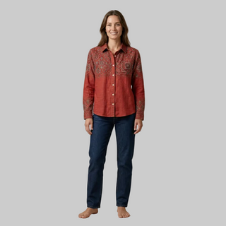 Full body shot of a model wearing an embroidered rust red long-sleeve shirt with dark blue jeans.