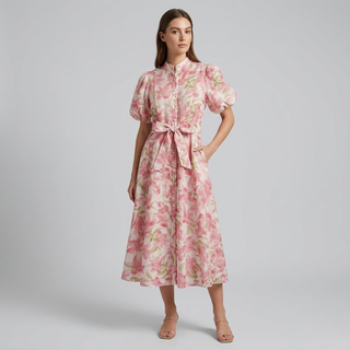 Side view of a female model in a pink floral puff-sleeve dress showing the flow of the midi-length skirt.