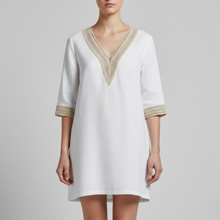 White dress with gold trim on a gray background