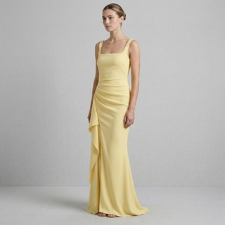 High-fashion editorial photo of a yellow sleeveless maxi dress featuring a fitted ruched bodice and floor-length ruffled skirt on a model.